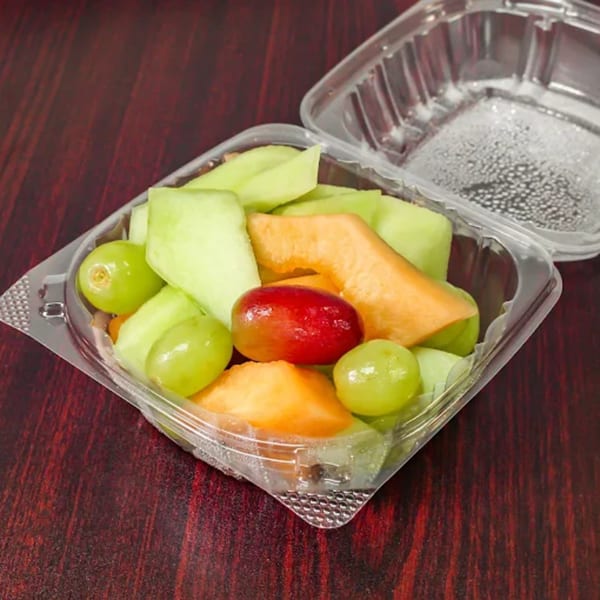 Fresh fruit cup with green grapes, red grapes, cantaloupe, and honeydew melon in a plastic container.