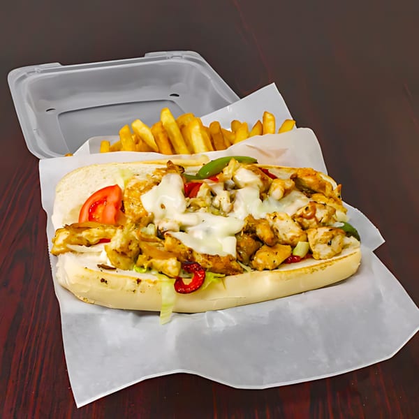 Chicken Philly cheesesteak with melted cheese, peppers, and tomatoes, served with fries in a takeout container.