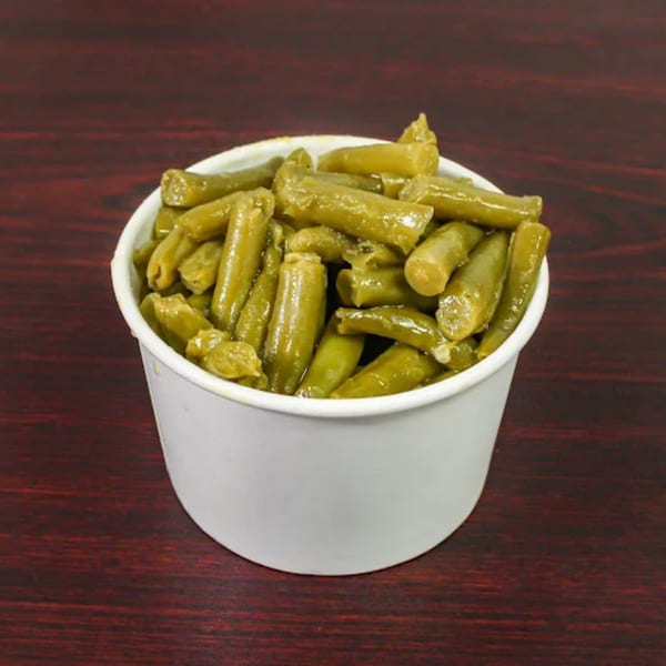 A white paper cup filled with cooked green beans, a side dish from American Fish & Chicken.