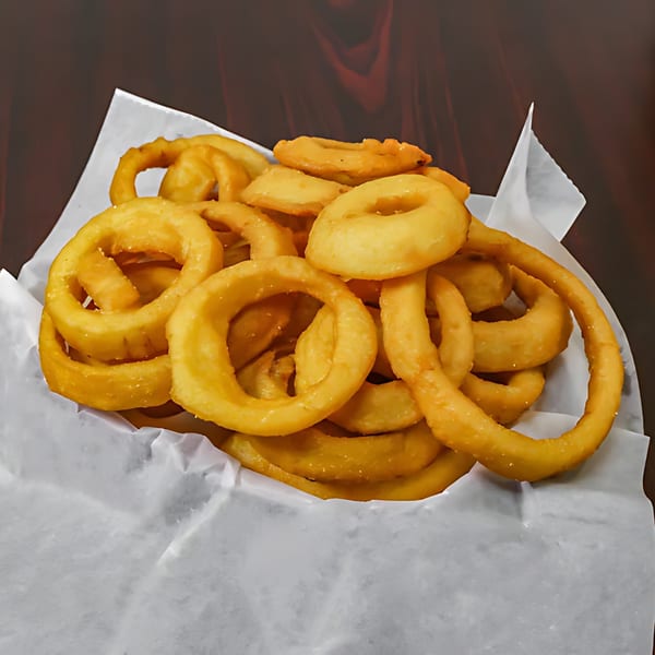 A basket of golden-brown, crispy onion rings from American Fish & Chicken, served on white paper.